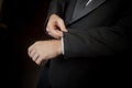 Hands of tuxedo wearing groom fixes cufflink.