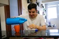 Caucasian man wearing a white T-shirt, filling a shot of bleach to drink, following the advice of the US President