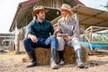 Caucasian man and woman farmers sit on straw and discuss about working with man explain the process and they look happy and relax