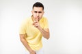 Caucasian man in a yellow T-shirt keeps a secret on a white isolated background