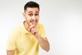 Caucasian man in a yellow T-shirt keeps a secret on a white isolated background