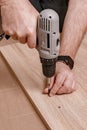 Caucasian mans hand holding an electric screwdriver. Man assembles furniture at home. Housework. Close-up. Vertical shot Royalty Free Stock Photo