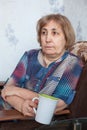 Caucasian mature woman holding tea cup, sitting in armchair in domestic room