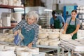 Elderly woman potter filling mould with melted clay