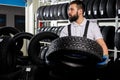 caucasian mechanic holding a tire and showing wheel tires at car repair service and auto store shop Royalty Free Stock Photo