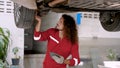 Caucasian mechanic with long hair Helping to repair a lifted car for suspension repair in garage. Technician Royalty Free Stock Photo