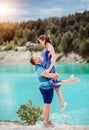 A caucasian man holds in his arms a beautiful caucasian woman in a dress by the river. A loving romantic couple in a Royalty Free Stock Photo