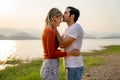 Caucasian man kiss on forehead of beautiful woman with sunset light near lake and look romantic for couple love stay together Royalty Free Stock Photo