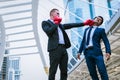 Caucasian man wear black suit and red boxing gloves punch to face of asian man. Royalty Free Stock Photo