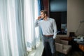 Caucasian mid adult businessman talking with mobile telephone in hotel room during business trip. Royalty Free Stock Photo