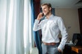 Caucasian mid adult businessman talking with mobile telephone in hotel room during business trip. Royalty Free Stock Photo