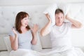 Caucasian middle age family couple angry shouting in bed. Conflict relationship concept. Husband cover ears by hands and wife