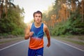 Caucasian middle age man athlete runs sunny summer day on asphalt road in the forest