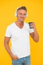 Caucasian middle-aged man drink takeaway coffee listening to music in casual fashion style yellow background, drinking Royalty Free Stock Photo