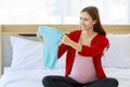 Caucasian millennial young happy female prenatal pregnant mother in casual pregnancy outfit jacket sitting smiling on bed in