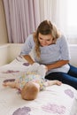 Caucasian mother and baby together on bed in bedroom doing physical fitness exercises yoga together Royalty Free Stock Photo