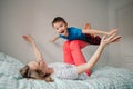 Caucasian mother and boy son playing in bedroom at home. Mom rocking child on her knees feet legs. Family having fun together.