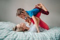 Caucasian mother and boy son playing in bedroom at home. Mom rocking child on her knees feet legs. Family having fun together. Royalty Free Stock Photo