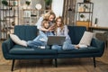 Caucasian mother and children sitting on couch using laptop, family enjoy distant talk by video call