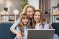 Caucasian mother and children sitting on couch using laptop, family enjoy distant talk by video call