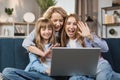 Caucasian mother and children sitting on couch using laptop, family enjoy distant talk by video call