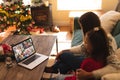 Caucasian mother and daughter making laptop christmas video call with diverse families