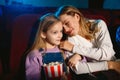 Young caucasian mother and daughter watching a film at a movie theater