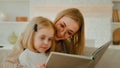 Caucasian mother in eyeglasses with little small cute daughter preschool child girl baby reading book in living room at Royalty Free Stock Photo