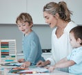 Caucasian mother helping son with homework. Proud mom looking at childs drawings learning about colours. Young mother at