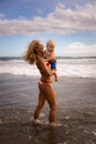 Caucasian mother holding child in her arms, walking along the beach. Happy childhood. Mum and son spending summer vacation Royalty Free Stock Photo