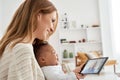 Caucasian mother holding crying african baby having meeting video call at home.