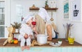 Caucasian mother and little daughter in white cap eat apple in kitchen.