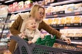 Caucasian mother shopping with her infant baby boy child choosing products in department of supermarket grocery store. Royalty Free Stock Photo