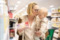 Caucasian mother shopping with her infant baby boy child choosing products in department of supermarket grocery store. Royalty Free Stock Photo