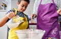 Caucasian mother teaching her son how to cook preparing the ingredients to make a cake