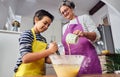 Caucasian mother teaching her son how to cook preparing the ingredients to make a cake