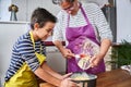 Caucasian mother teaching her son how to cook preparing the ingredients to make a cake