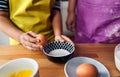 Caucasian mother teaching her son to cook and preparing the ingredients to make a cake. Child breaking an egg