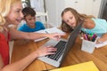 Caucasian mother using laptop and doing homework with her daughter and son smiling at home Royalty Free Stock Photo