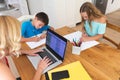 Caucasian mother using laptop and her daughter and son doing homework in kitchen Royalty Free Stock Photo