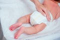 Caucasian mother using wet wipes,applying baby powder before putting diapers on her four month old baby in bed at home Royalty Free Stock Photo