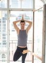 Sporty man practicing yoga in white room with big window. tree pose