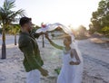 Caucasian newlywed couple holding hands and dancing at wedding ceremony at beach during sunset Royalty Free Stock Photo