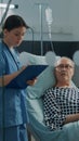 Caucasian nurse checking on elder patient in hospital ward Royalty Free Stock Photo