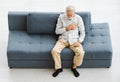 Caucasian old senior elderly gray hair and bearded man lying down close eyes on sofa in living room at home alone holding hands on Royalty Free Stock Photo