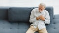 Caucasian old senior elderly gray hair and bearded man lying down close eyes on sofa in living room at home alone holding hands on Royalty Free Stock Photo