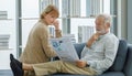 Caucasian old senior elderly happy lover couple grandparent gray bearded husband and wife sitting relaxing resting on sofa reading Royalty Free Stock Photo