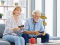 Caucasian old senior elderly lovely happy grandparents married couple husband and wife sitting playing competition on console Royalty Free Stock Photo