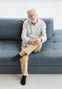 Caucasian old senior elderly stressed depressed worried upset gray hair and bearded man sitting close eyes on sofa in living room Royalty Free Stock Photo