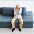 Caucasian old senior elderly stressed depressed worried upset gray hair and bearded man sitting on sofa in living room at home Royalty Free Stock Photo